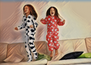 two young girls in pajamas jumping on couch