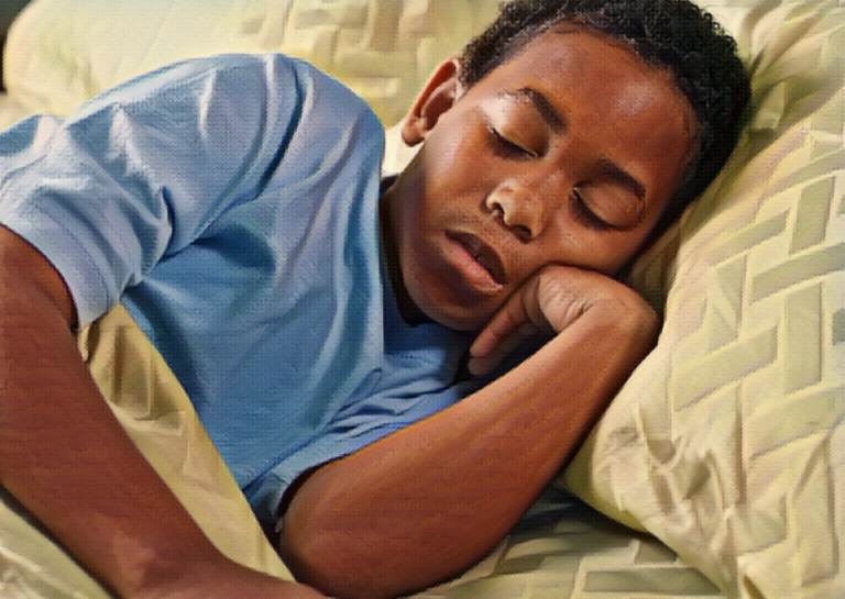 school age boy sleeping in bed laying face on hand