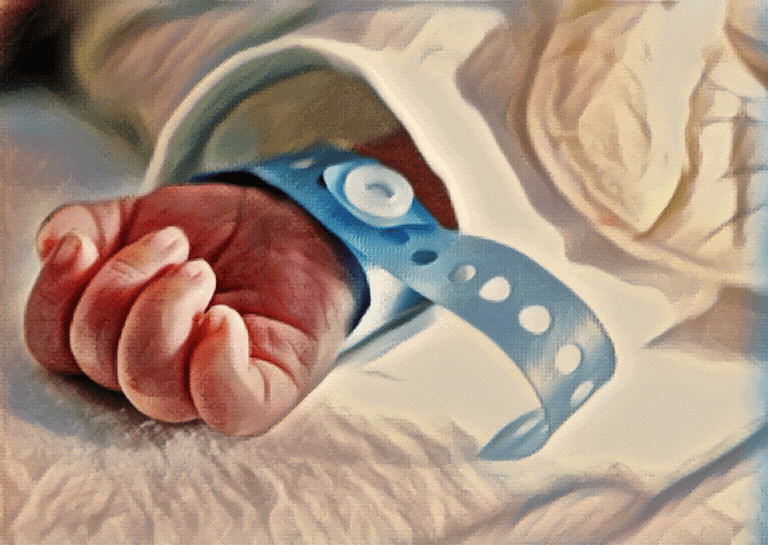 newborn baby hand and arm wearing blue hospital wristband