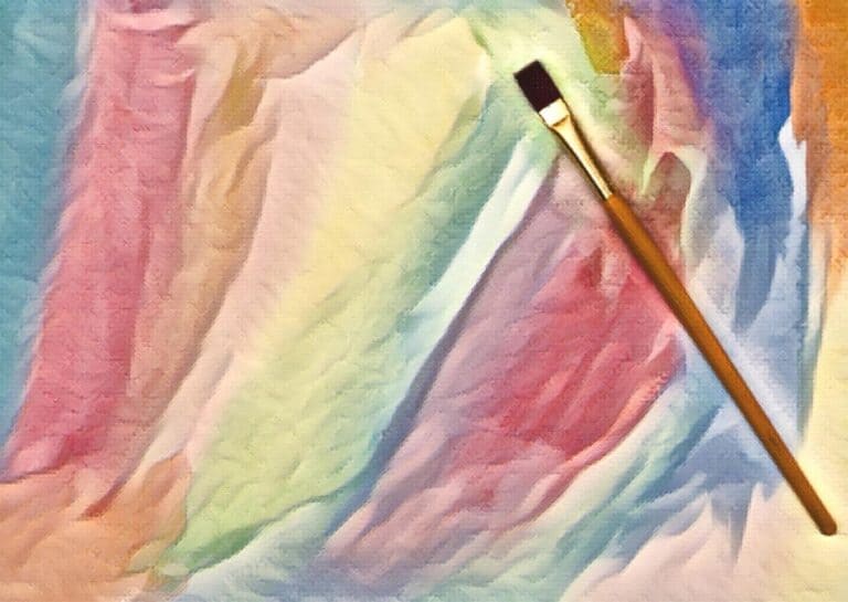 paint brush sitting on top of a rainbow multicolor painted surface